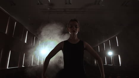 SLOW-MOTION:-prima-ballet-rehearses-a-solo-performance-standing-on-the-stage-of-the-theater-in-smoke-in-a-black-dress-in-the-light.