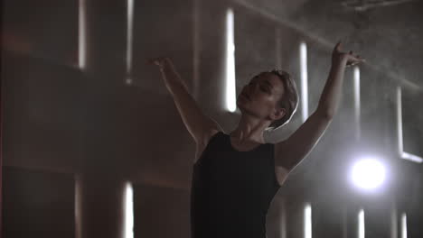 Close-up-of-ballet-dancer-as-she-practices-exercises-on-dark-stage-or-studio.-Ballerina-shows-classic-ballet-pas.-Slow-motion.-Flare-gimbal-shot.