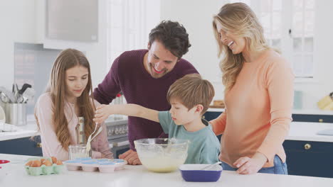 Familia-Con-Dos-Niños-En-La-Cocina-De-Casa-Divirtiéndose-Horneando-Pasteles-Juntos