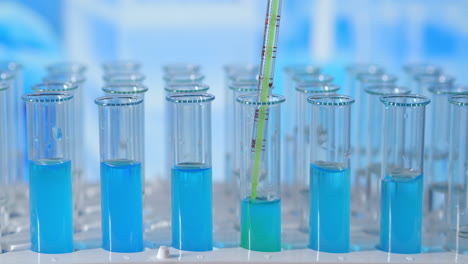 Wissenschaftler-Spritzen-Chemikalien-In-Reagenzgläser.-Reagenzglas-Mit-Farbiger-Flüssigkeit-Auf-Dem-Labortisch-Im-Hintergrund-Der-Glaskolben.-Aus-Glaspipette-In-Mit-Blauem-Licht-Beleuchtetes-Reagenzglas-Gegossen.-Hochwertiges-4K-Filmmaterial