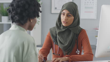 Female-Doctor-Or-Consultant-Wearing-Headscarf-Having-Meeting-With-Female-Patient-To-Discuss-Scans