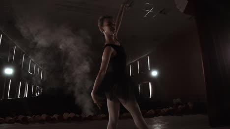 Una-Elegante-Bailarina-Bailando-Elementos-De-Ballet-En-La-Oscuridad-Con-Luz-Y-Humo-En-El-Fondo-En-Cámara-Lenta