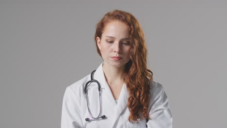 Studio-Portrait-Of-Stressed-Female-Doctor-With-Stethoscope-In-White-Coat-Against-Plain-Background