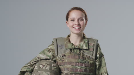 Retrato-De-Estudio-De-Una-Joven-Soldado-Sonriente-Con-Uniforme-Militar-Sobre-Fondo-Liso