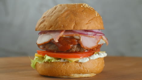 Ein-Hamburger-Auf-Einem-Brett,-überall-Liegen-Verstreut-Pommes-Frites.-Nahaufnahme-Eines-Köstlichen,-Frischen,-Hausgemachten-Burgers-Mit-Salat,-Käse,-Zwiebeln-Und-Tomaten-Auf-Einem-Rustikalen-Holzbrett-Auf-Dunklem-Hintergrund
