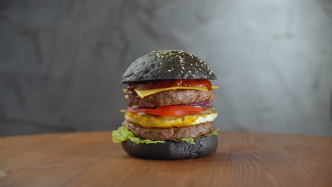 Black-Burger.-Ein-Burger-Mit-Schwarzen-Brötchen,-Saftigen-Marmor-Rindfleischscheiben,-Käse,-Frischem-Salat-Und-Barbecuesauce.