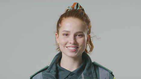 Studio-Portrait-Of-Smiling-Young-Female-Paramedic-Against-Plain-Background