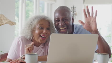 Älteres-Paar-Sitzt-Zu-Hause-Am-Tisch-Und-Führt-Videoanrufe-Auf-Dem-Laptop