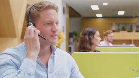 Geschäftsmann-Trägt-Telefon-Headset-Und-Spricht-Mit-Anrufer-Im-Kundendienstzentrum