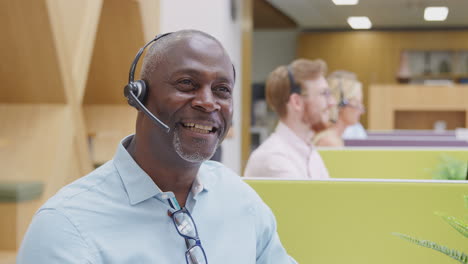 Reifer-Geschäftsmann-Trägt-Telefon-Headset-Und-Spricht-Mit-Anrufer-Im-Kundendienstzentrum