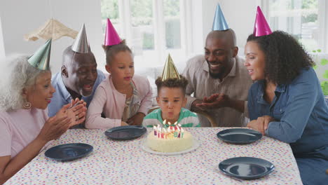 Mehrgenerationenfamilie-Sitzt-Am-Tisch-Und-Feiert-Den-Geburtstag-Des-Jungen,-Während-Er-Kerzen-Ausbläst