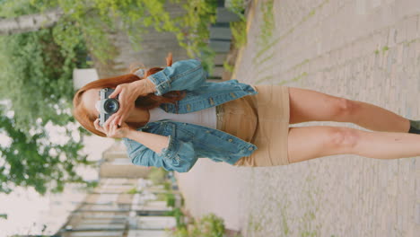Vertical-Video-Of-Young-Woman-In-City-Taking-Photo-On-Digital-Camera-To-Post-To-Social-Media