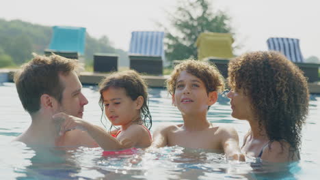 Porträt-Einer-Multiethnischen-Familie,-Die-Sich-Im-Gemeinsamen-Sommerurlaub-Im-Schwimmbad-Entspannt