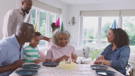 Eine-Familie-Aus-Mehreren-Generationen-Sitzt-Am-Tisch-Und-Feiert-Den-Geburtstag-Der-Großmutter,-Während-Sie-Kerzen-Ausbläst