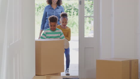 Excited-Children-Helping-Mother-To-Carry-Boxes-Into-New-Home-On-Moving-In-Day