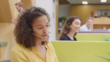 Businesswoman-Wearing-Phone-Headset-Talking-To-Caller-In-Customer-Services-Centre