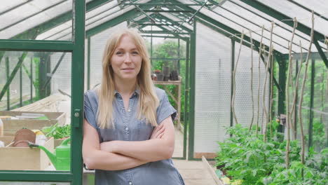 Portrait-Of-Woman-Growing-Vegetables-Standing-In-Doorway-Of-Greenhouse-And-Folding-Arms
