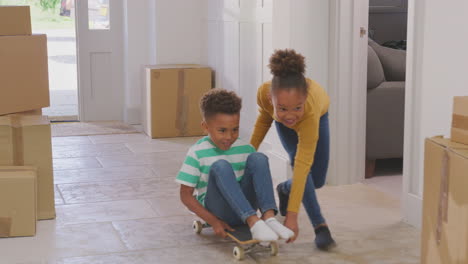Girl-Pushing-Brother-On-Skateboard-In-Between-Boxes-On-Moving-In-Day