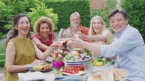 Portrait-Of-Mature-Friends-Making-A-Toast-With-Wine-At-Summer-Party-In-Garden-At-Home
