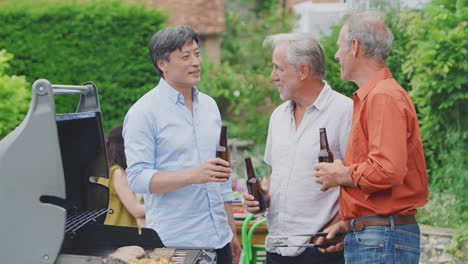Drei-ältere-Männliche-Freunde-Kochen-Gemeinsam-Im-Freien-Barbecue-Und-Trinken-Bier-Zu-Hause