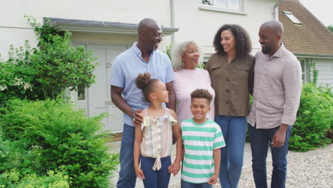 Portrait-Of-Smiling-Multi-Generation-Family-Standing-Outside-Home-Together