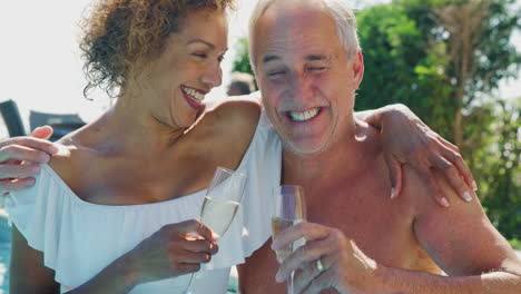 Älteres-Ehepaar-Im-Ruhestand,-Das-Sich-Im-Sommerurlaub-Im-Schwimmbad-Entspannt-Und-Champagner-Trinkt