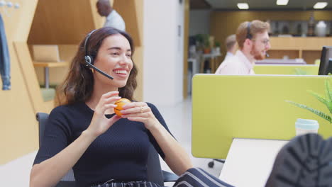 Businesswoman-Wearing-Headset-Playing-With-Stress-Ball-Talking-To-Caller-In-Customer-Services-Centre