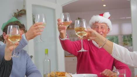 Erwachsene-Stoßen-Mit-Wein-An,-Während-Die-Familie-Mit-Mehreren-Generationen-Gemeinsam-Das-Weihnachtsessen-Isst