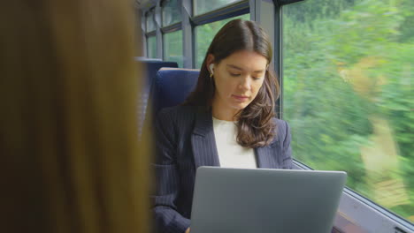 Mujer-De-Negocios-Con-Auriculares-Inalámbricos-Viajando-Al-Trabajo-En-Tren-Trabajando-En-Una-Computadora-Portátil