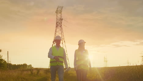 Coworking-engineers-with-tablets-on-solar-plant.-Adult-men-and-women-in-hardhats-using-tablets-while-standing-outdoors-on-transformer-platform.-Transportation-of-clean-energy.-Wind-energy-delivery
