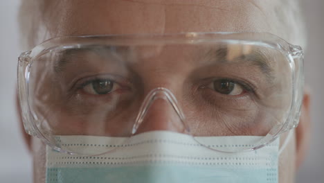 Portrait-of-confident-doctor-man-face-close-up.-eyes-with-safety-glasses-and-protective-mask.-Research-Laboratory-Officer.-2019-Novel-Coronavirus-2019-nCoV-pandemic-isolation-concept.-High-quality-4k-footage