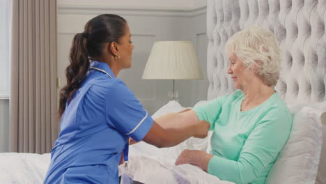 Senior-Woman-At-Home-In-Bed-Having-Blood-Pressure-Taken-By-Female-Care-Worker-In-Uniform