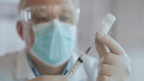 Close-up-shot-of-unrecognizable-nurse-or-doctor-in-gloves-filling-syringe-from-ampule-with-covid-19-vaccine.-Nurse-filling-injection-syringe-from-vial.-High-quality-4k-footage