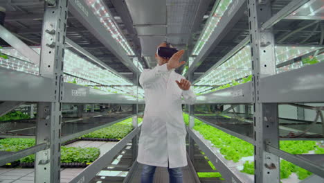 Wissenschaftler,-Ein-Mann-Im-Weißen-Laborkittel,-Nutzen-Eine-Virtual-Reality-Brille-Auf-Dem-Bauernhof-Mit-Hydrokultur-Zur-Bewässerungssteuerung.-Genetiker-Analysieren-Die-Zusammensetzung-Von-Gemüse,-Das-Auf-Plantagen-Wächst