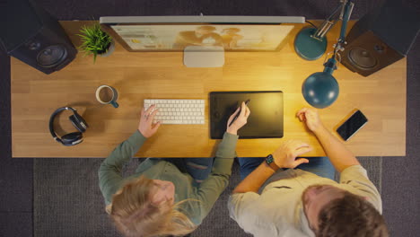 Overhead-View-Of-Male-And-Female-Graphic-Designers-Working-At-Computer-Screen-In-Creative-Office