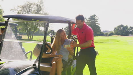 Couple-Playing-Round-On-Golf-Together-Sitting-In-Buggy-With-Score-Card
