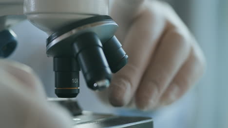 Close-up-of-microscope-oculars-being-directed-at-a-sample-on-a-piece-of-glass.-Close-up-shot-of-sample-slide-and-microscope-with-metal-lens-at-laboratory.-High-quality-4k-footage