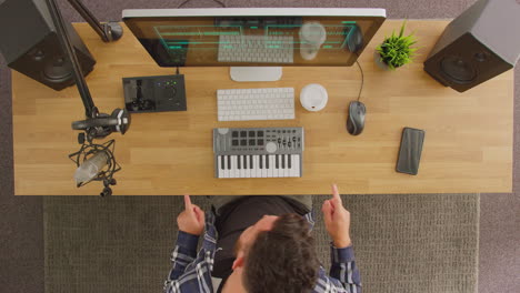 Overhead-View-Of-Male-Musician-Dancing-At-Workstation-With-Keyboard-And-Microphone-In-Studio