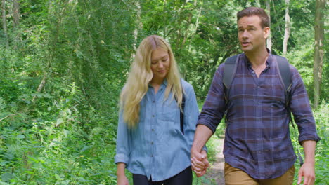 Loving-Couple-Holding-Hands-In-Countryside-Hiking-Along-Path-Through-Forest-Together