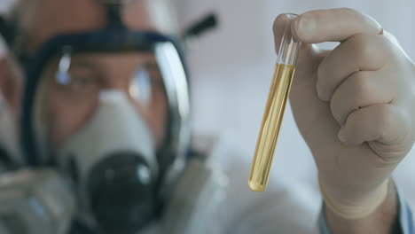 A-male-Professor-examines-a-test-tube-with-a-yellow-solution-with-a-virus-Covid.-High-quality-4k-footage