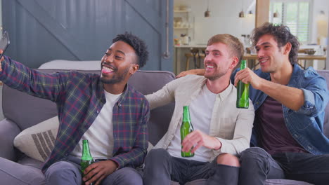 Multikulturelle-Gruppe-Männlicher-Freunde,-Die-Zu-Hause-Auf-Dem-Sofa-Sitzen,-Bier-Trinken-Und-Für-Ein-Selfie-Posieren