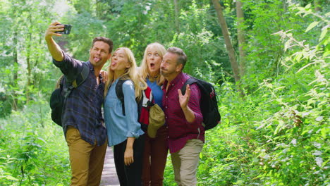 Group-Of-Friends-Posing-For-Selfie-In-Countryside-Taking-Picture-On-Phone-As-They-Hike-Along-Path