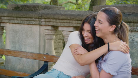 Same-Sex-Female-Couple-Sightseeing-Around-Oxford-UK-Sitting-On-Bench-And-Hugging