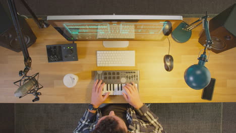 Overhead-View-Of-Male-Musician-At-Workstation-With-Keyboard-And-Microphone-In-Studio