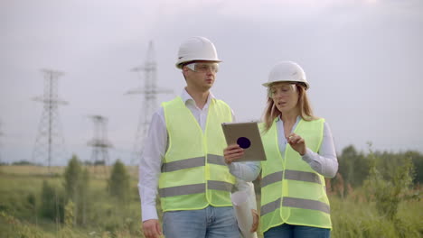 Engineering-working-on-High-voltage-tower-Check-the-information-on-the-tablet-computer-two-employees-man-and-woman