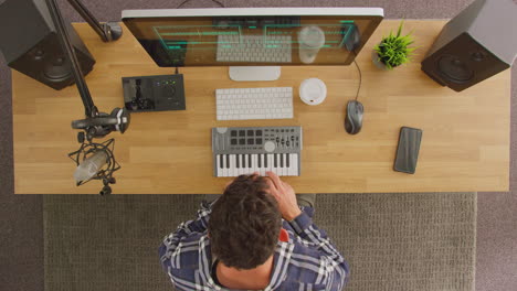 Overhead-View-Of-Male-Musician-At-Workstation-With-Keyboard-And-Microphone-In-Studio