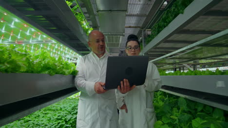 Genetic-engineering.-Doctors-in-white-coats-look-and-adjust-the-work-of-the-vertical-farm-checking-the-plants-and-looking-into-the-screens-of-tablets