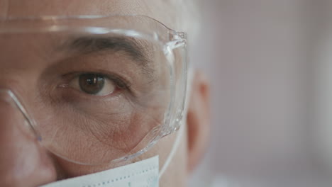 Male-doctor-or-nurse-in-uniform-mask-and-glasses-looking-straight-at-camera.-Close-up-of-eye.-slow-motion