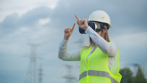 Portrait-of-a-modern-woman-of-the-Comptroller-of-the-engineer-conducting-the-inspection-via-virtual-reality-glasses-and-a-white-helmet-dressed-in-uniform-in-the-background-the-towers-of-power.