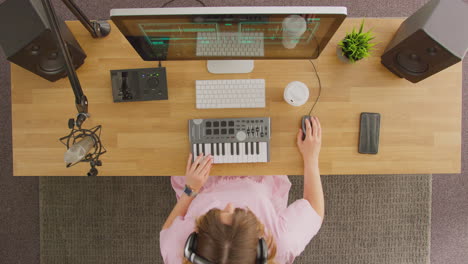 Overhead-View-Of-Female-Musician-At-Workstation-With-Keyboard-And-Microphone-In-Studio
